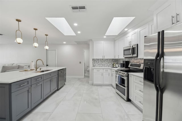 kitchen with visible vents, white cabinets, decorative light fixtures, stainless steel appliances, and a sink