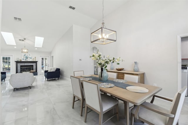 dining room with high vaulted ceiling, a skylight, a tile fireplace, and visible vents