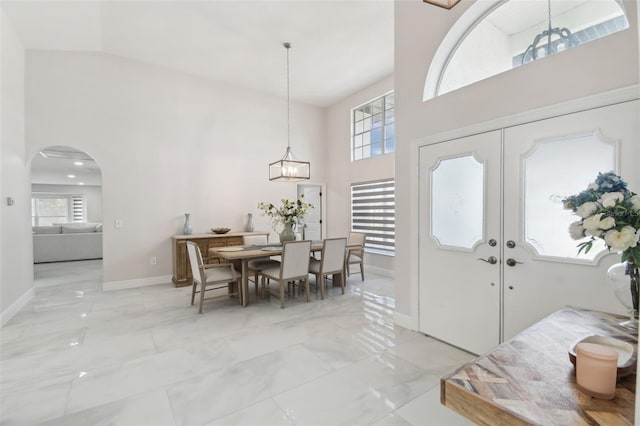 entryway with arched walkways, a towering ceiling, baseboards, marble finish floor, and french doors