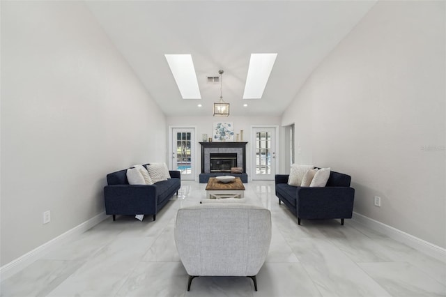 living room with high vaulted ceiling, a skylight, visible vents, baseboards, and a tiled fireplace