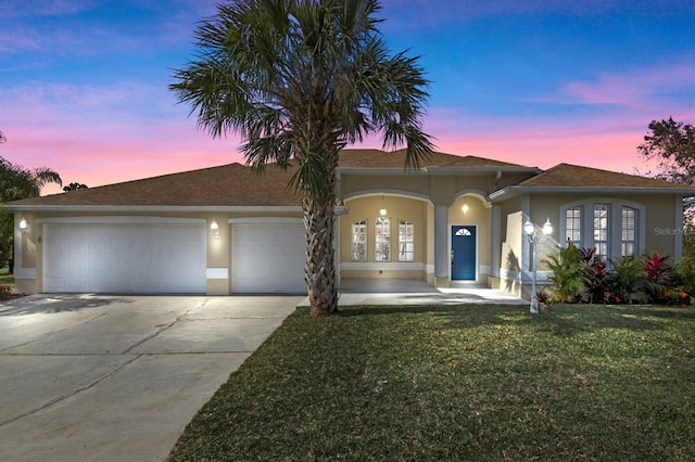 view of front of house with french doors, stucco siding, concrete driveway, a front yard, and a garage