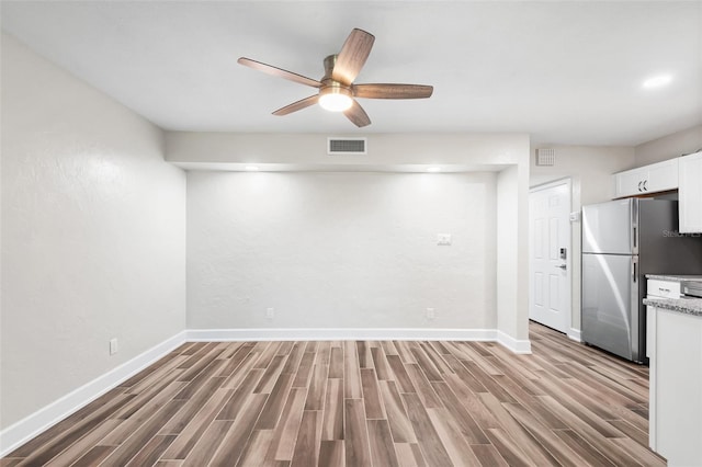 interior space with freestanding refrigerator, light wood finished floors, visible vents, and white cabinetry