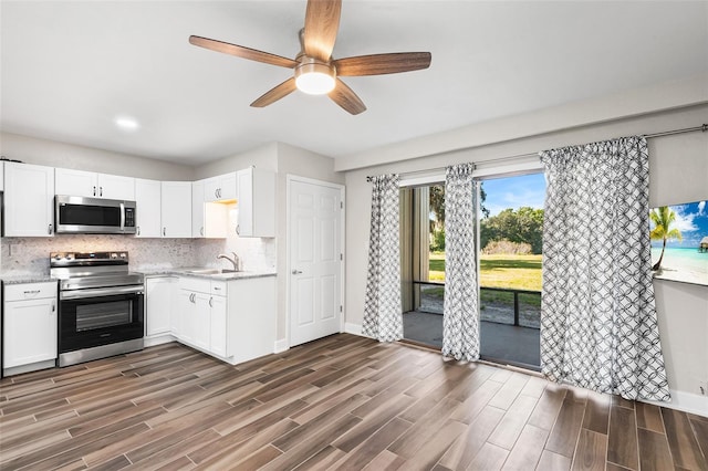 kitchen with appliances with stainless steel finishes, white cabinets, backsplash, and dark wood-style floors