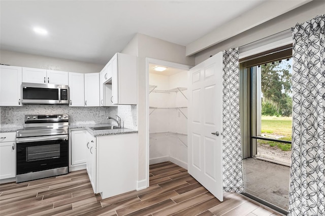 kitchen featuring stainless steel appliances, tasteful backsplash, a sink, and light stone counters