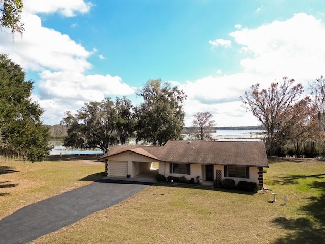 single story home with a water view, driveway, an attached carport, and a front yard