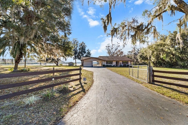 view of front of property featuring driveway, an attached garage, fence, and a front yard