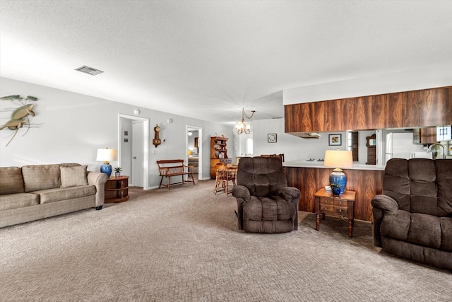 living room with a chandelier, a textured ceiling, carpet flooring, and visible vents