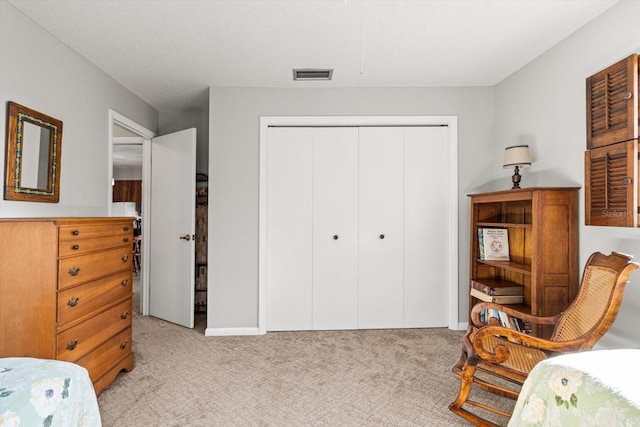 bedroom with a closet, visible vents, and light carpet