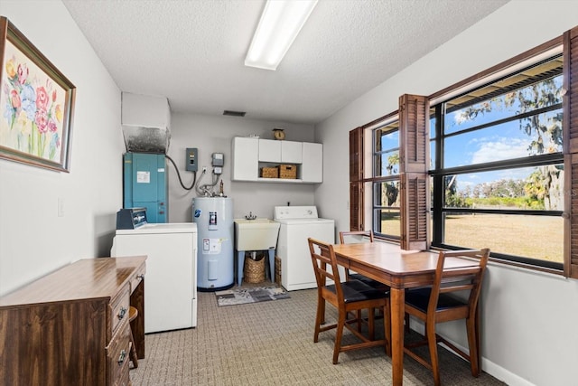 clothes washing area featuring light colored carpet, water heater, cabinet space, washing machine and dryer, and a textured ceiling