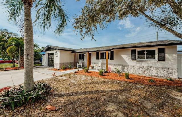 ranch-style home featuring stucco siding, covered porch, a garage, stone siding, and driveway