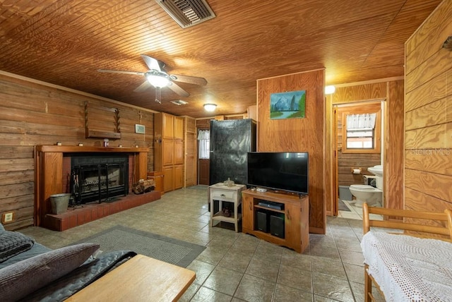 living area featuring a brick fireplace, wooden ceiling, wooden walls, and visible vents