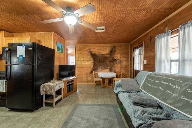 living area with light tile patterned floors, wooden walls, wood ceiling, a ceiling fan, and visible vents