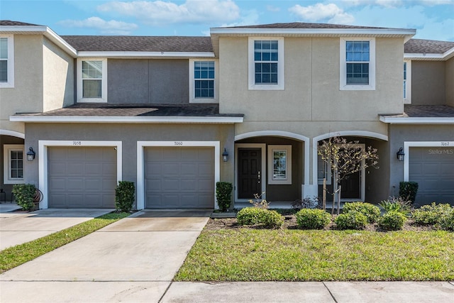 multi unit property with concrete driveway, roof with shingles, and stucco siding