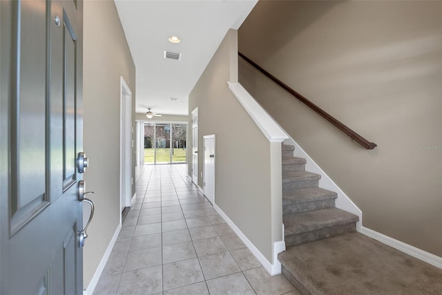 foyer entrance with light tile patterned floors, a ceiling fan, visible vents, stairs, and baseboards