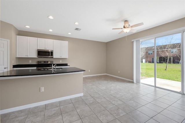 kitchen featuring baseboards, white cabinets, dark countertops, appliances with stainless steel finishes, and a sink