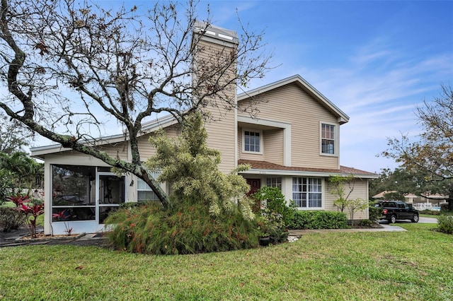 view of side of home featuring a sunroom, a yard, and a chimney