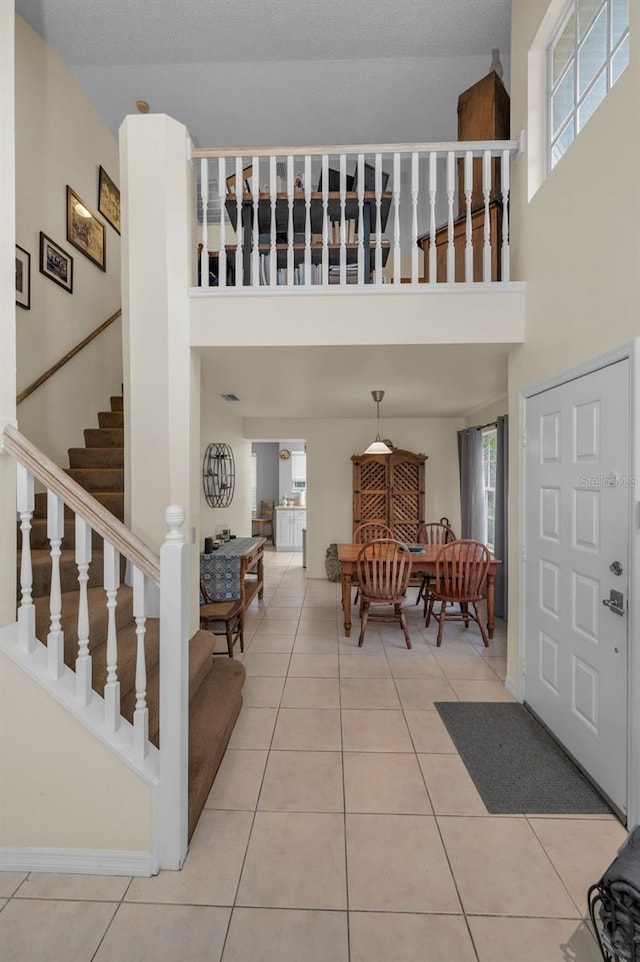 foyer entrance featuring tile patterned flooring, plenty of natural light, and stairway