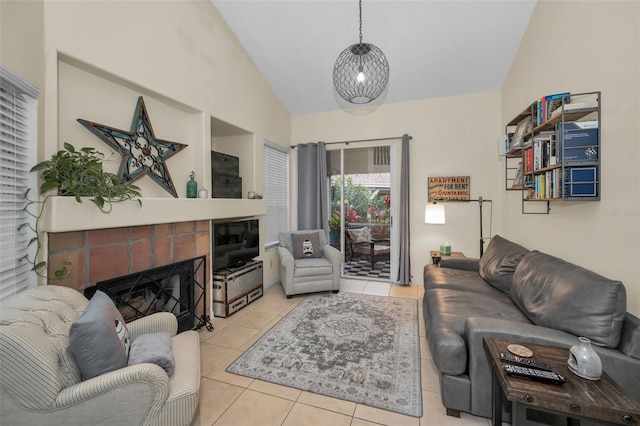 living room with lofted ceiling, a tiled fireplace, and light tile patterned flooring