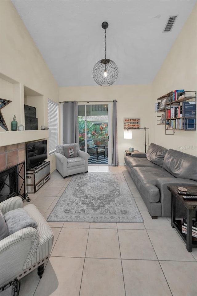 living area featuring lofted ceiling, light tile patterned flooring, a fireplace, and visible vents