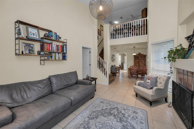 living room featuring light tile patterned floors, stairway, a high ceiling, ceiling fan, and baseboards