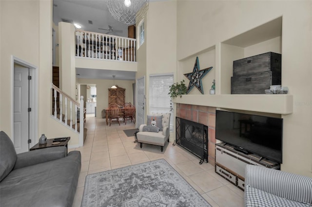 living room with ceiling fan, stairs, a fireplace, and light tile patterned flooring