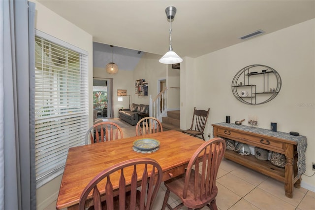 dining area featuring light tile patterned flooring, visible vents, and stairs