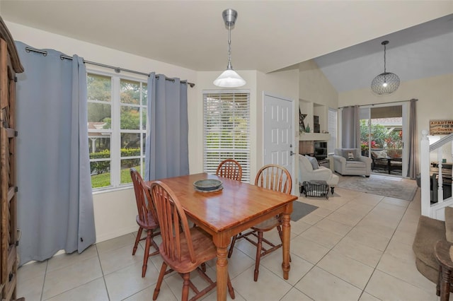 dining area featuring lofted ceiling, baseboards, light tile patterned flooring, and a glass covered fireplace