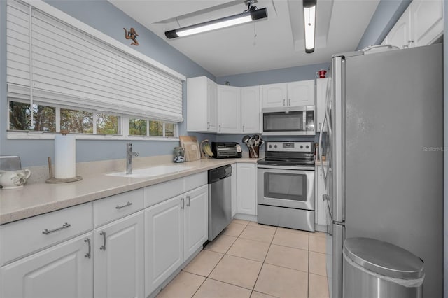 kitchen featuring light tile patterned floors, stainless steel appliances, light countertops, white cabinetry, and a sink