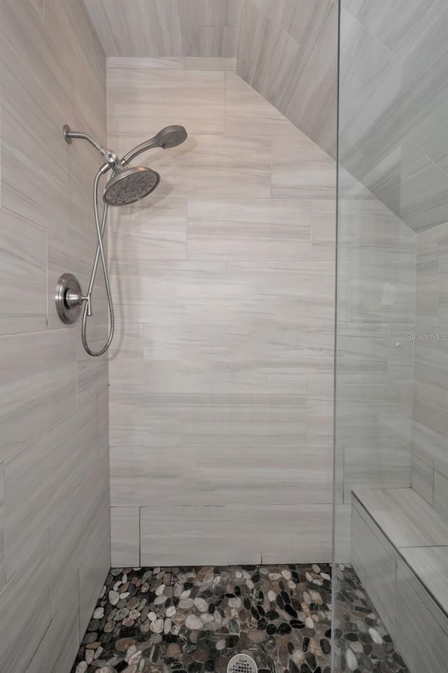 bathroom with a tile shower and vaulted ceiling