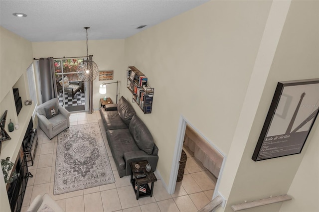 living area with a textured ceiling, light tile patterned flooring, and visible vents