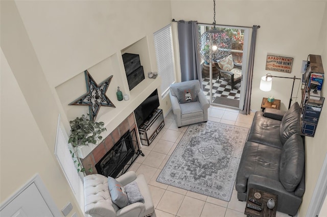 living room featuring a tile fireplace, a towering ceiling, and light tile patterned floors