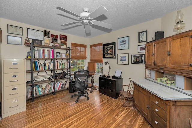 home office featuring a textured ceiling, a ceiling fan, and wood finished floors