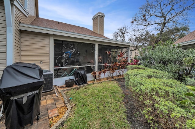 view of yard featuring a sunroom and central air condition unit