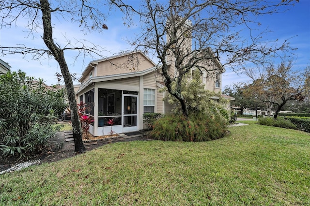 view of side of property with a sunroom and a lawn