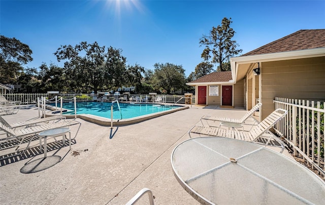 community pool with a patio area and fence