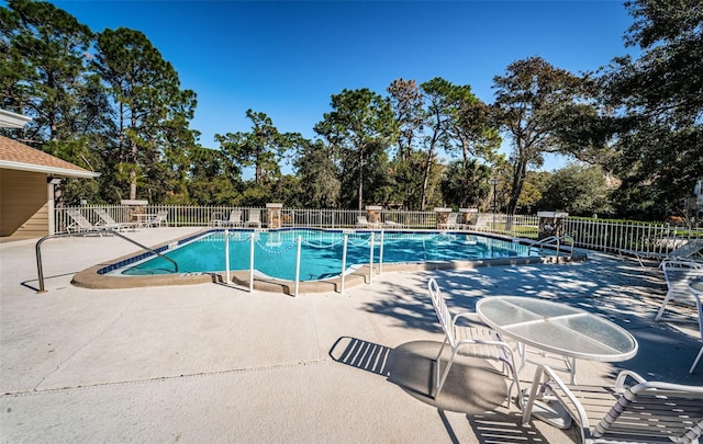 community pool with a patio and fence