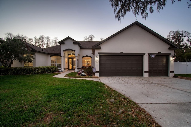 view of front of property with a garage, a front yard, concrete driveway, and stucco siding