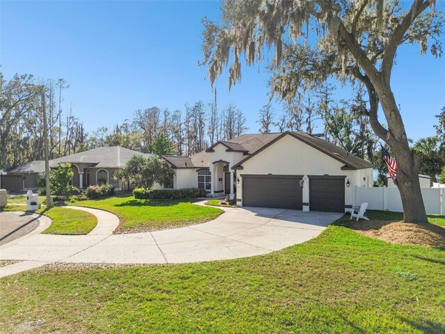 ranch-style home featuring a garage, concrete driveway, fence, a front lawn, and stucco siding