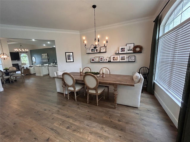 dining area with ornamental molding, wood finished floors, a fireplace, and an inviting chandelier