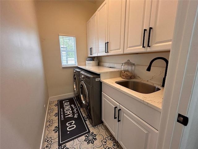 washroom with light tile patterned floors, a sink, baseboards, washer and dryer, and cabinet space