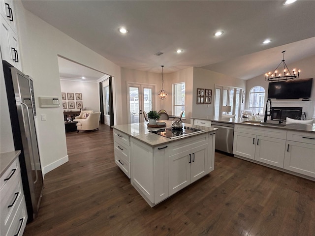 kitchen featuring white cabinets, open floor plan, hanging light fixtures, appliances with stainless steel finishes, and light stone countertops