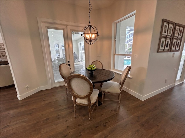 dining room with a notable chandelier, dark wood finished floors, and baseboards