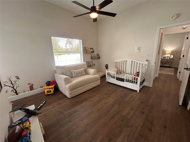 bedroom featuring baseboards, a ceiling fan, lofted ceiling, dark wood-type flooring, and a nursery area