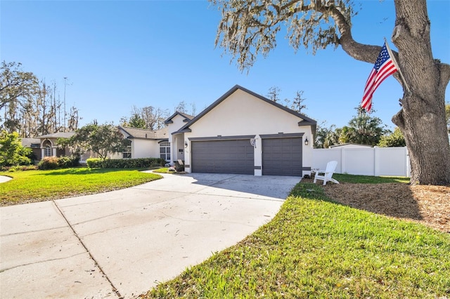 view of front of house featuring stucco siding, concrete driveway, an attached garage, a front yard, and fence