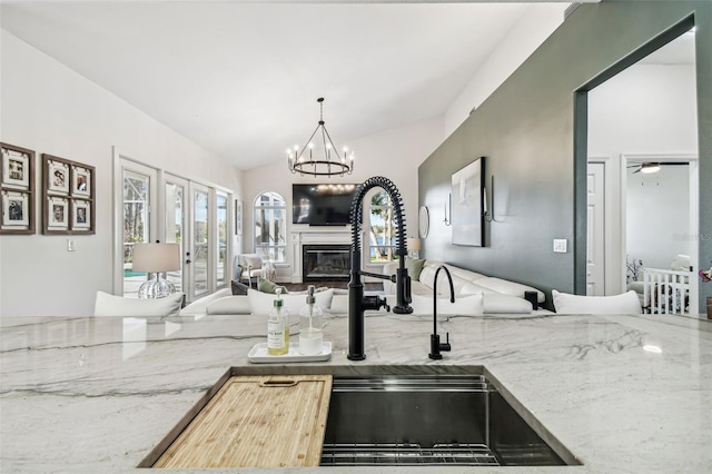 1301 Jen Ma Jo Ln, Lutz, FL 33549 - kitchen featuring open floor plan, light stone counters, vaulted ceiling, pendant lighting, and a chandelier
