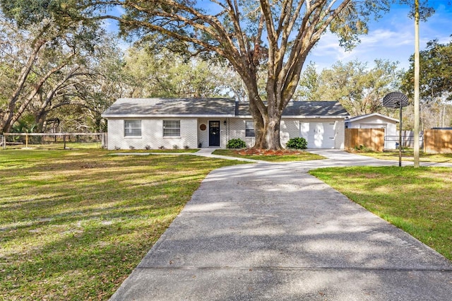 view of front of house with a front yard, brick siding, driveway, and fence