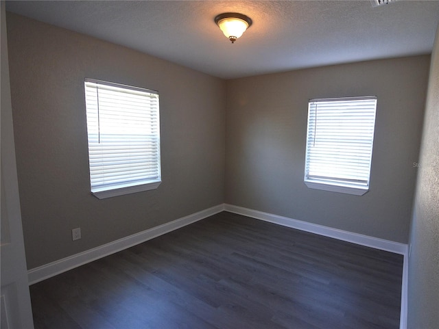 unfurnished room with dark wood-style floors, plenty of natural light, and baseboards