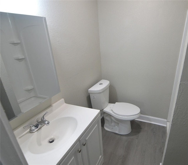 bathroom featuring toilet, wood finished floors, vanity, and baseboards