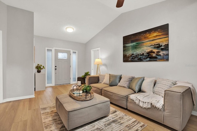 living area featuring vaulted ceiling, light wood finished floors, a ceiling fan, and baseboards