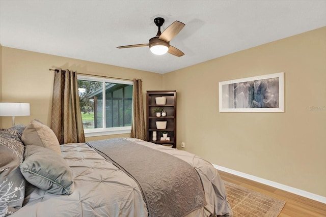 bedroom with light wood-style floors, ceiling fan, and baseboards